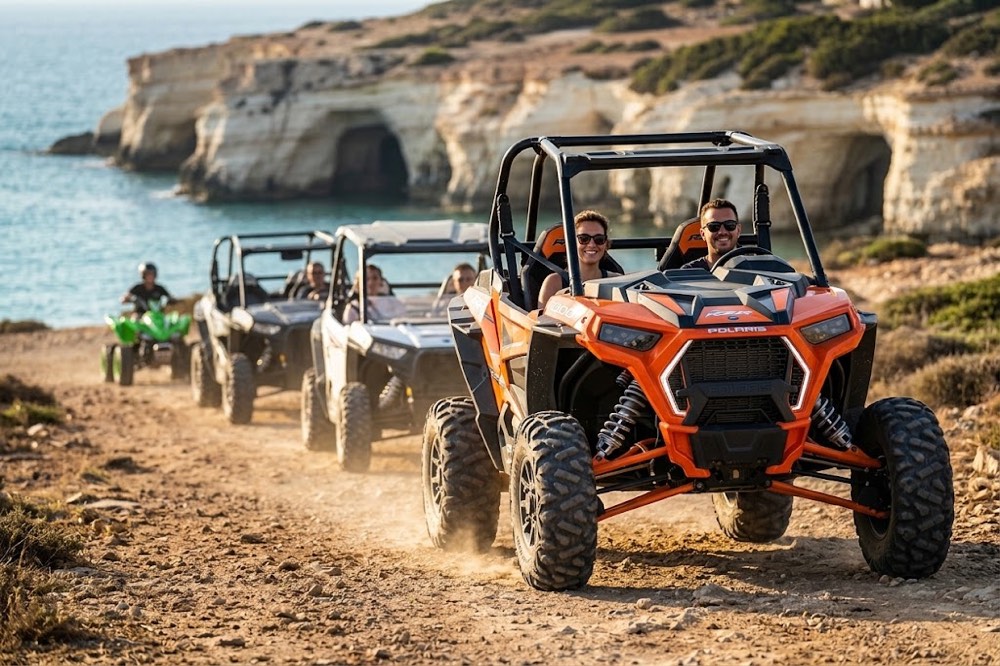 Convoy of Polaris buggies on a coastal track heading toward the Sea Caves near Paphos at golden hour