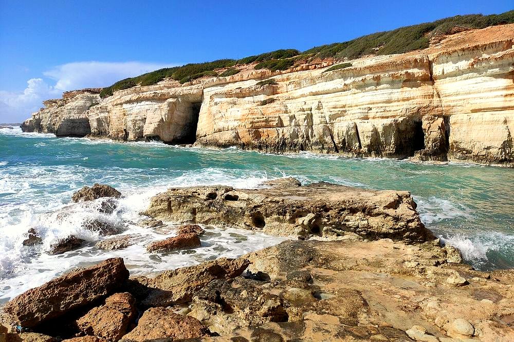 Limestone sea cliffs with cave openings and turquoise water at the Peyia Sea Caves, Cyprus