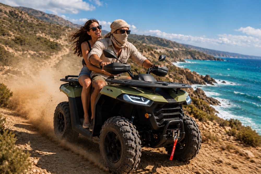 Couple riding a Segway 500cc quad along a coastal dirt track above turquoise water near Paphos
